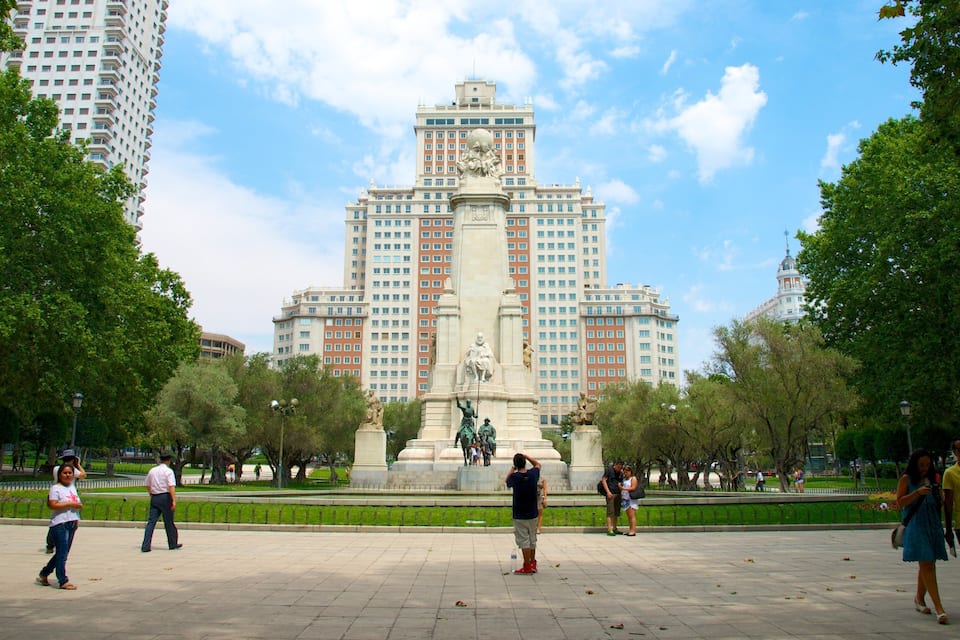 A large public square with a central monument, surrounded by trees and tall buildings.