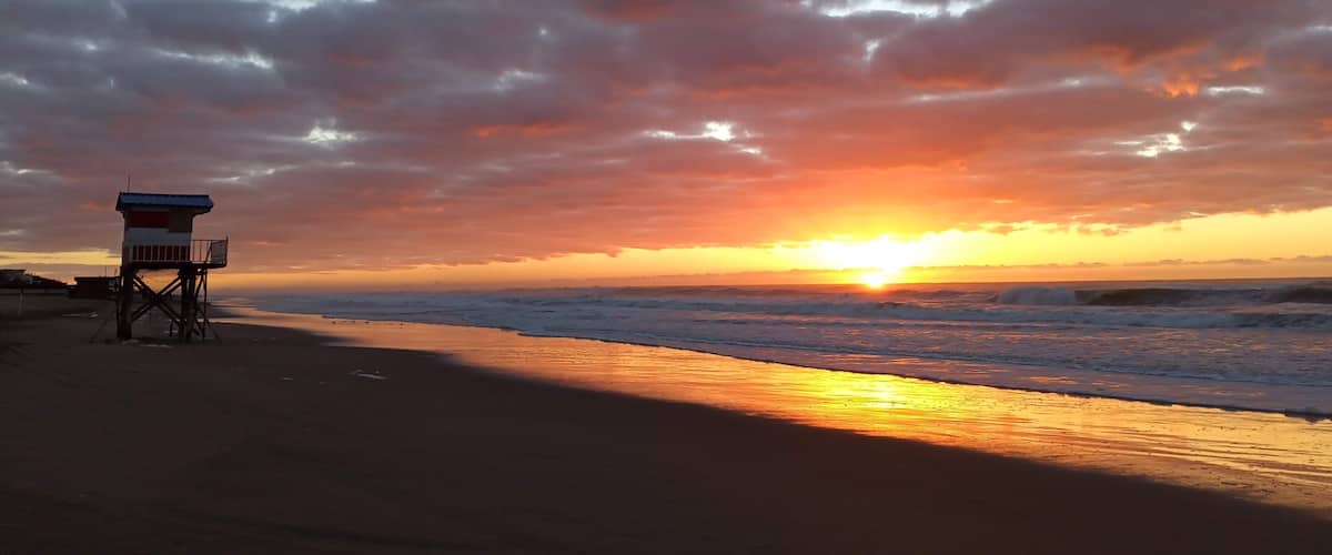 A beach with a lifeguard tower at sunset.