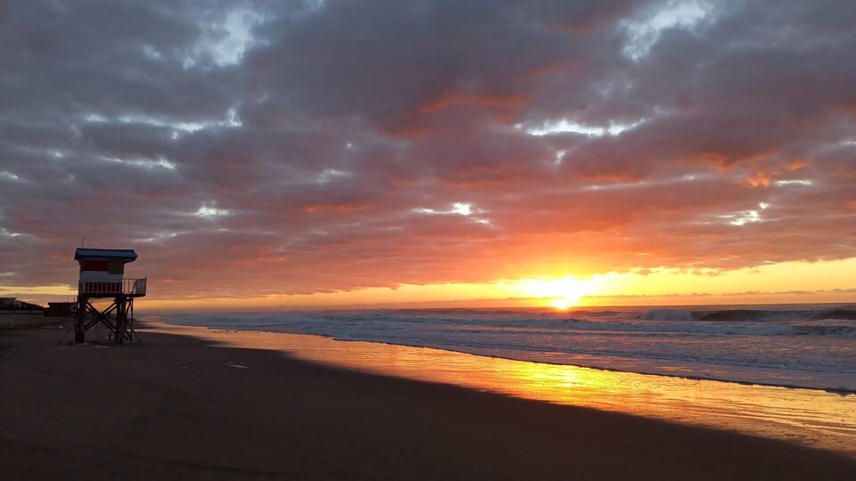 A beach with a lifeguard tower at sunset.