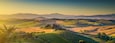 Scenic Tuscany landscape panorama with rolling hills and harvest fields in golden morning light, Val d'Orcia, Italy.