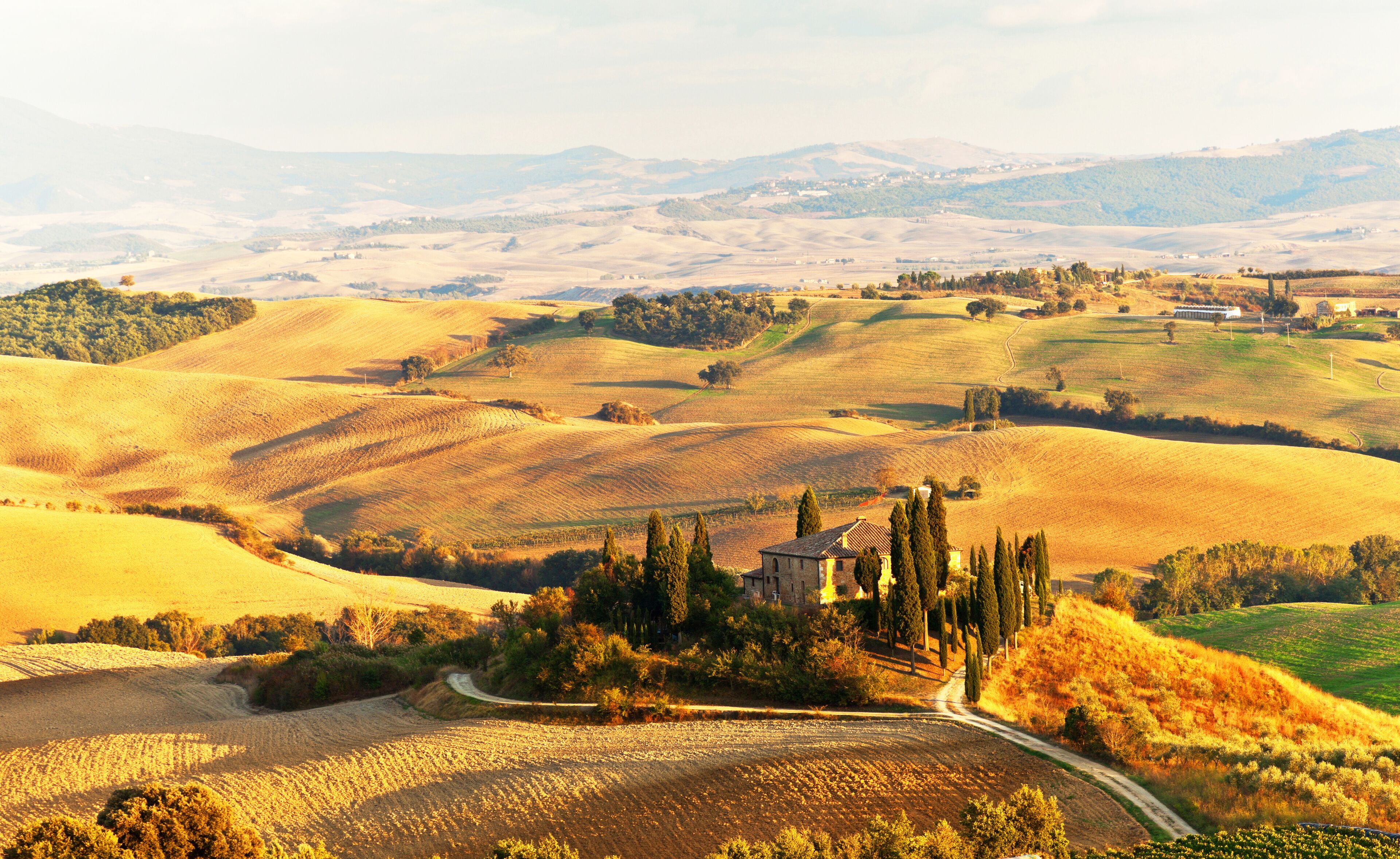 Italy. Pienza.  Beautiful Tuscany autumn rural landscape with cleaned fields and a farmhouse with cypress trees in the setting sun. Val d'Orcia natural Park