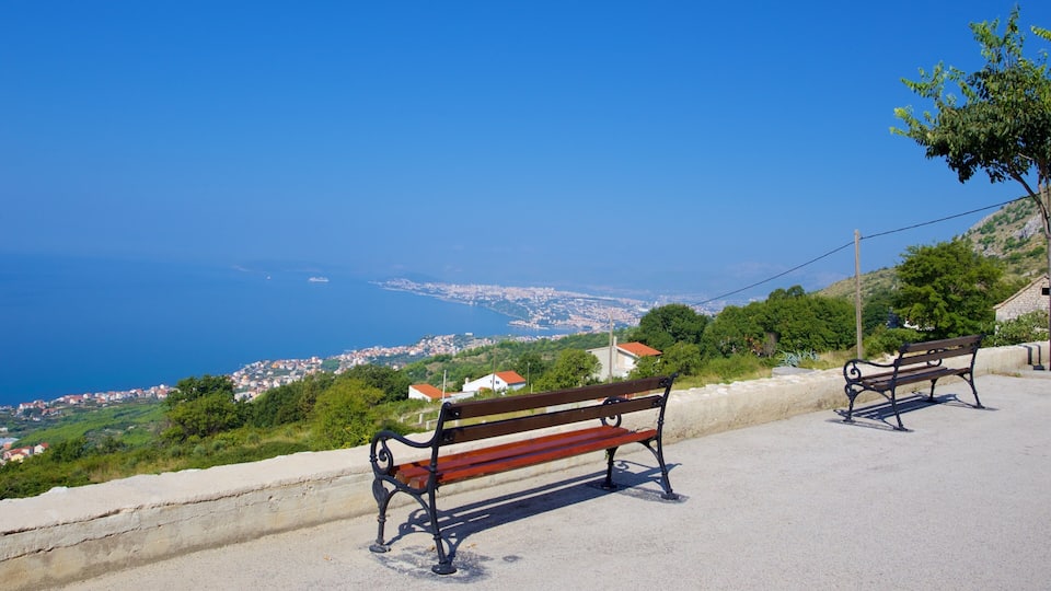 A coastal view with two benches overlooking a town and the sea.