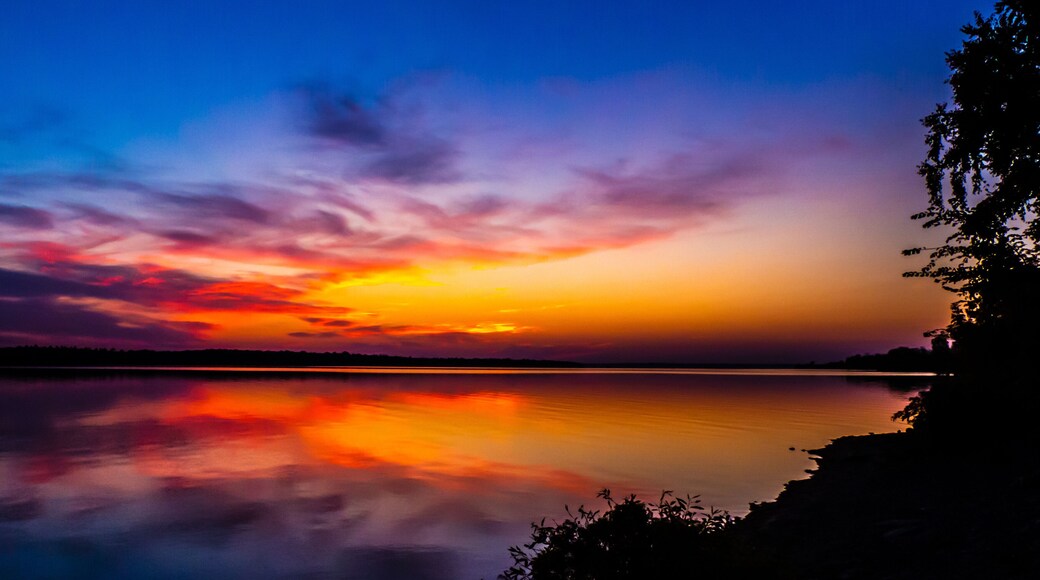 Beautiful scenic view of a vibrant sunrise over the ottawa river with the silhouette of trees on a cold morning in october.