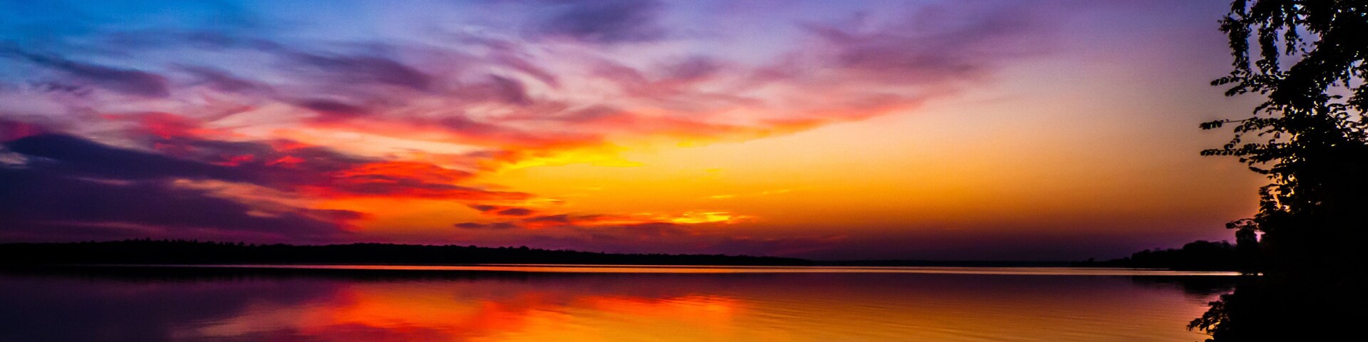 Beautiful scenic view of a vibrant sunrise over the ottawa river with the silhouette of trees on a cold morning in october.