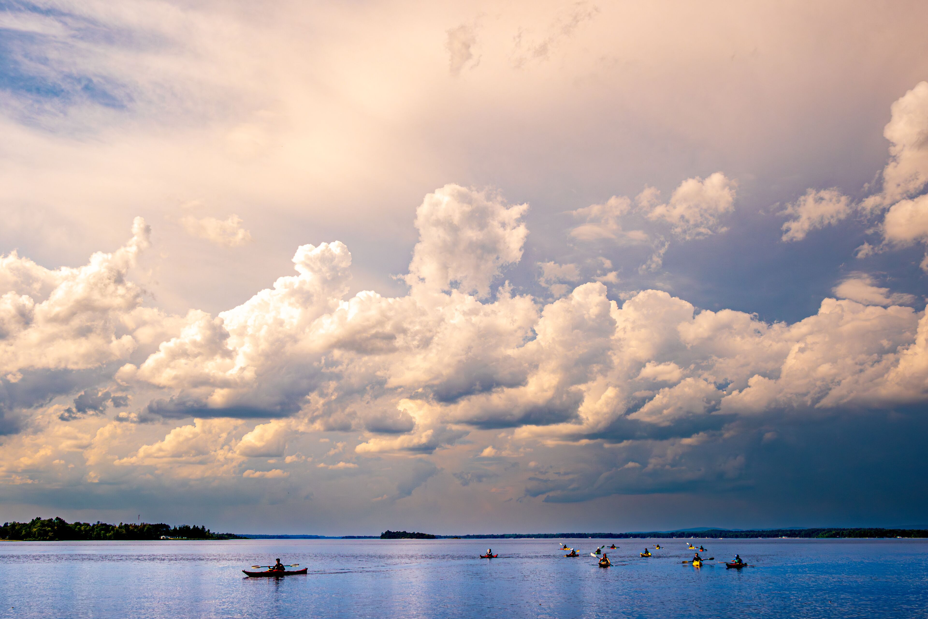 sea kayakers paddling in on the ottawa river  pembroke ontario under huge dramatic white clouds
