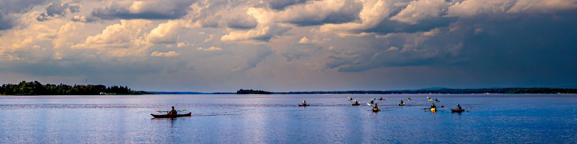 sea kayakers paddling in on the ottawa river pembroke ontario under huge dramatic white clouds