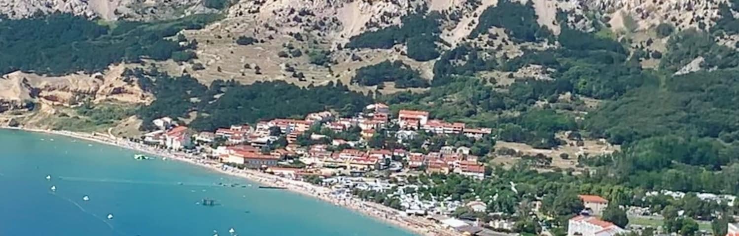 Un pueblo costero con playa, casas y montañas al fondo.