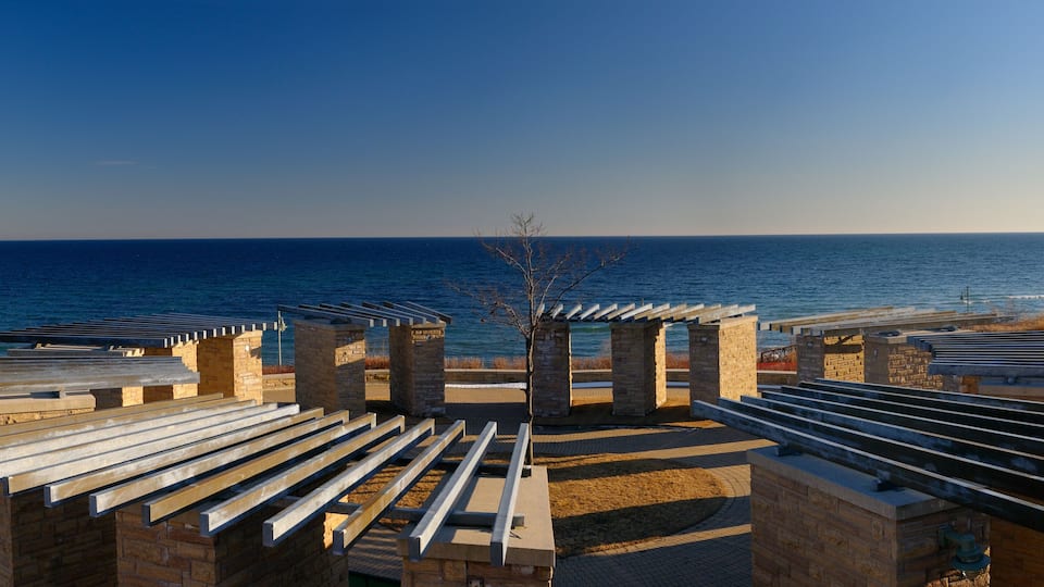 A coastal promenade with stone structures and benches overlooking the sea.