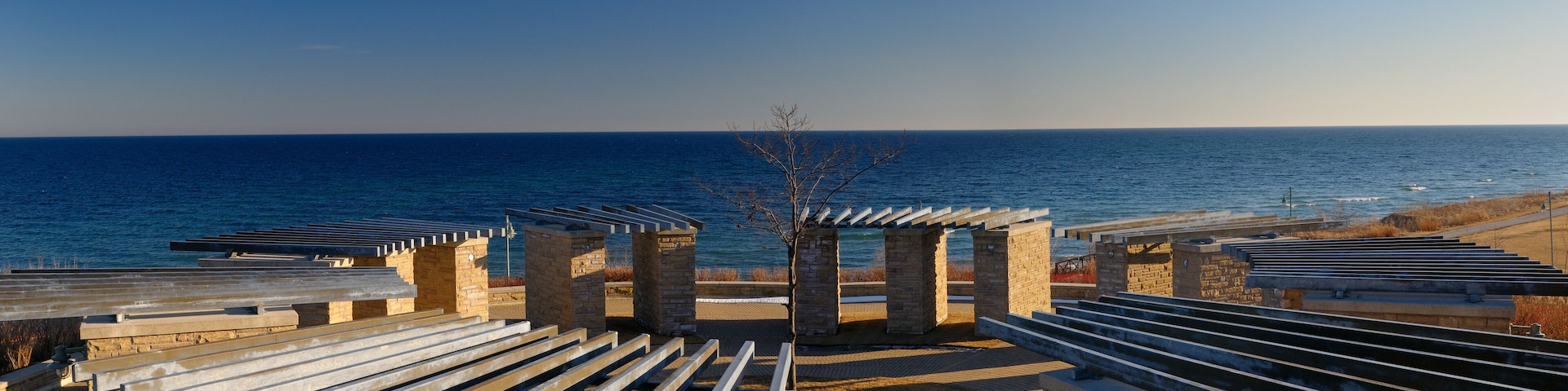 A coastal promenade with stone structures and benches overlooking the sea.