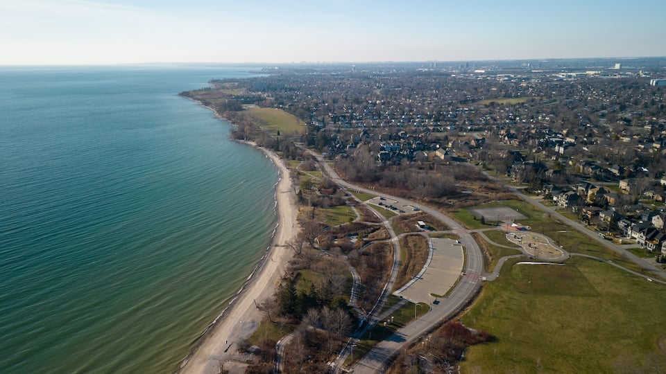 An aerial view of a coastal town with a beach, roads, and residential areas.