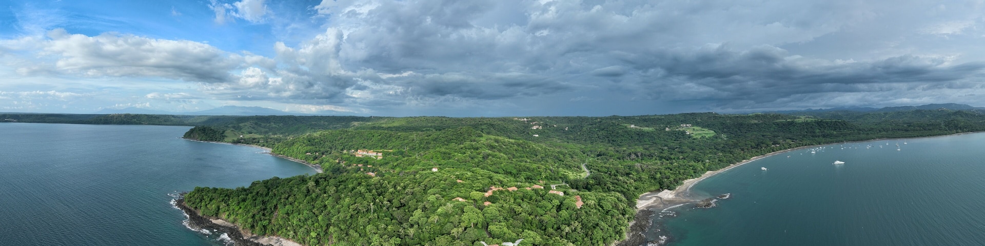 An aerial view of a lush, green island surrounded by calm waters, with a clear sky above.
