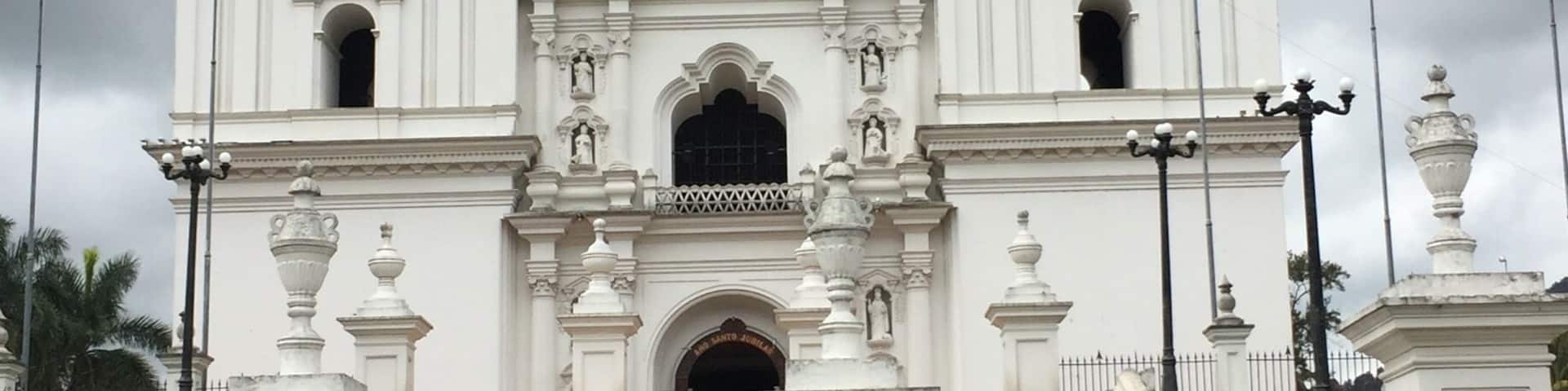 A white colonial-style church with three towers and a central entrance.