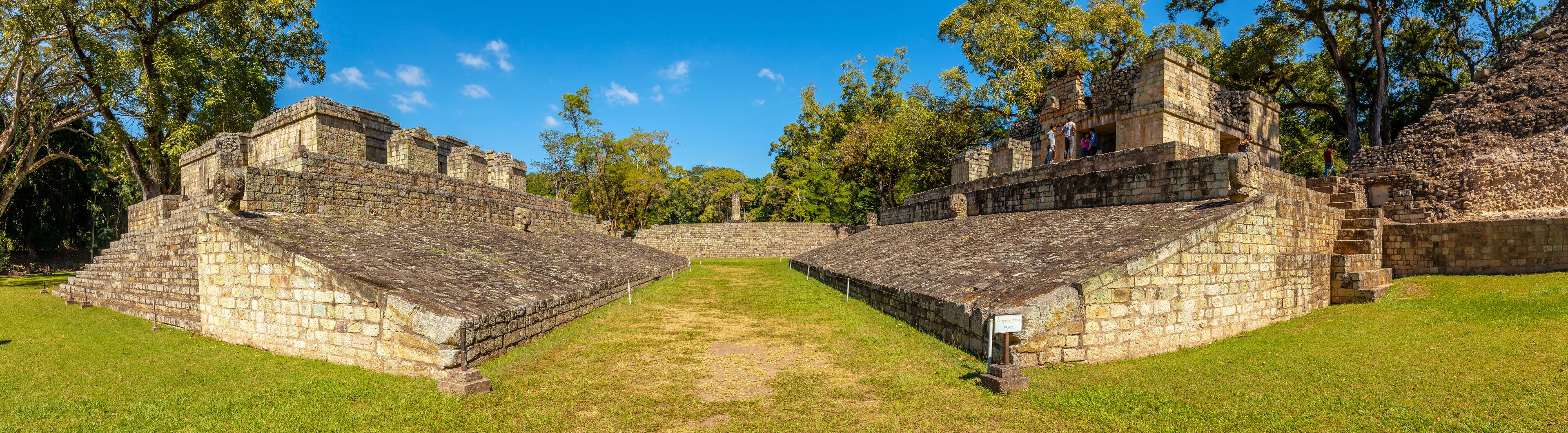 Antiguas estructuras de piedra con un espacio abierto central rodeado de árboles.