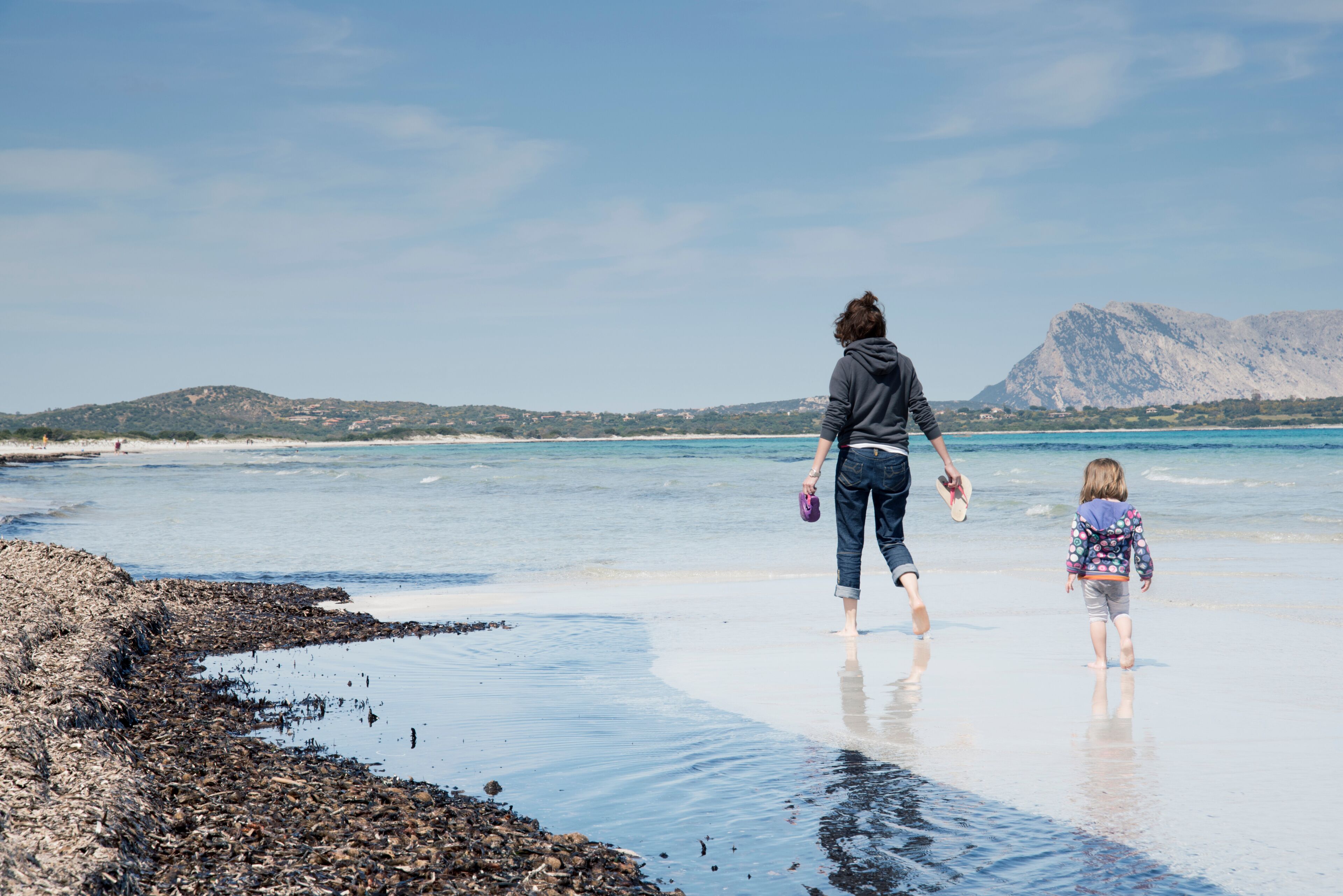 Mother with daughter walking on Cala Brandinchi beach, San Teodoro, Sardinia, Italy