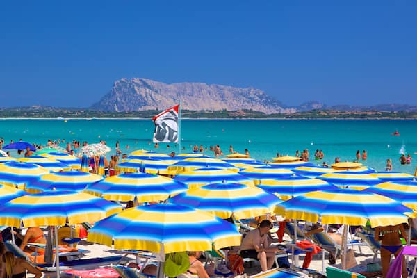Una spiaggia affollata con molti ombrelloni colorati e persone che si godono il mare.
