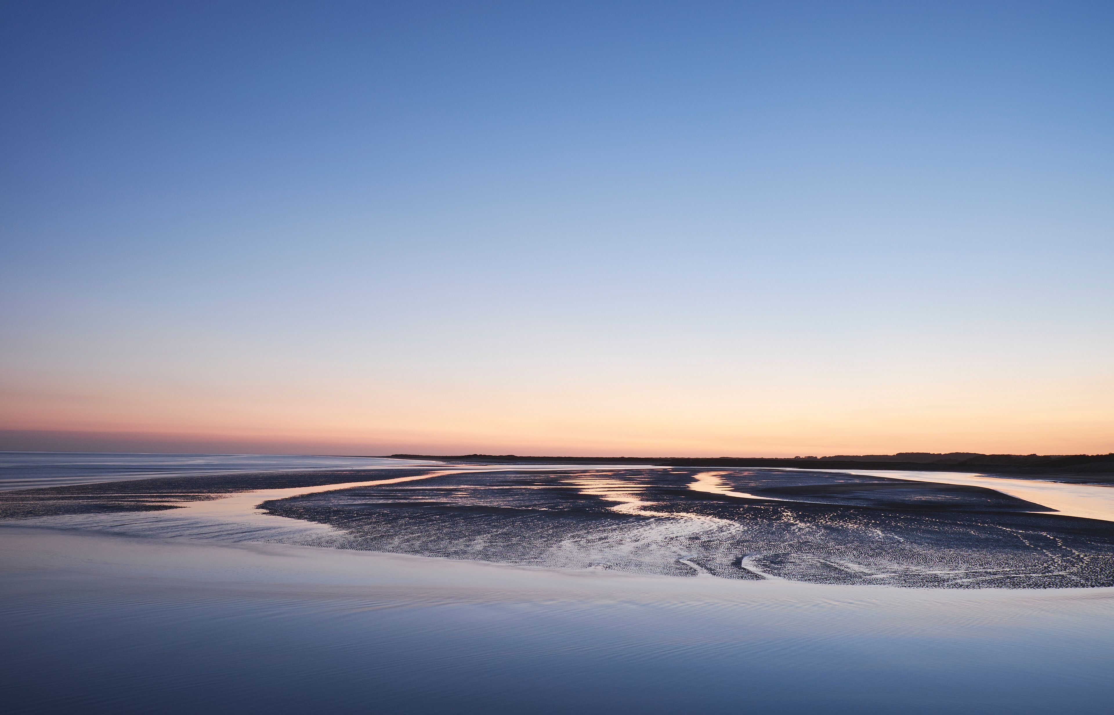Colourful twilight sky at low tide. Burry Port, Wales, UK.
