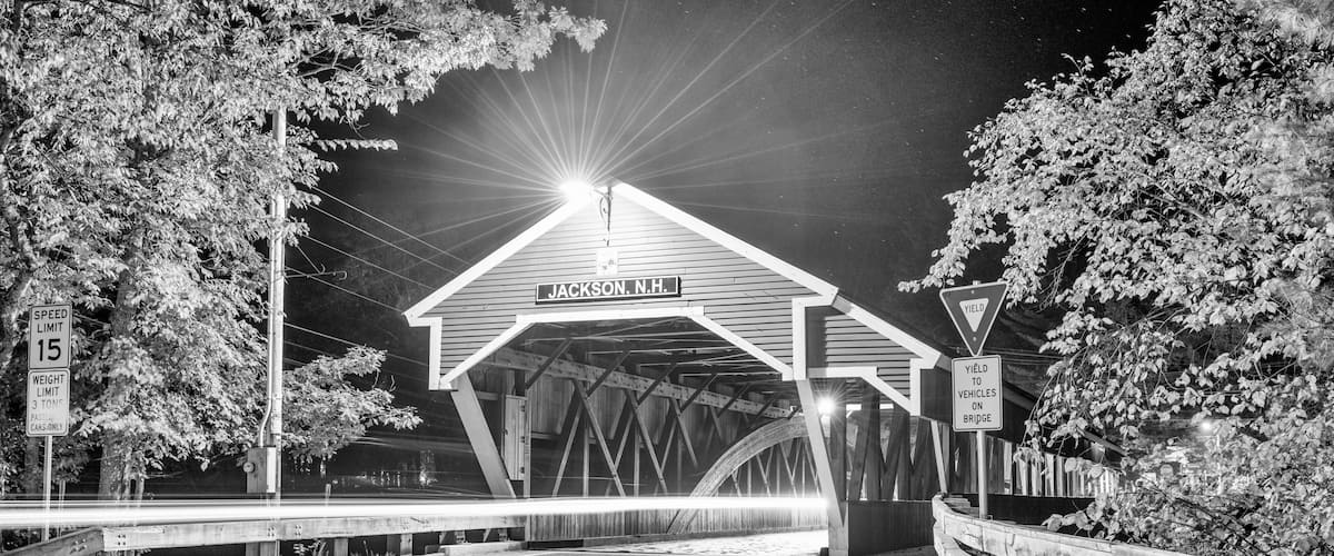A covered bridge with 'JACKSON, N.H.' sign, speed limit 15, and 'NO PARKING ANY TIME' sign.