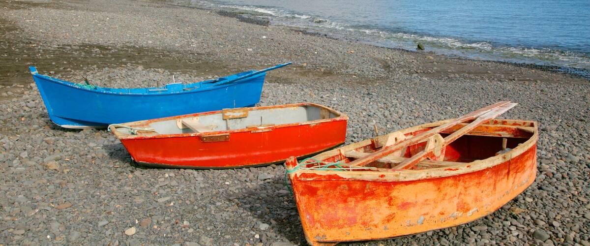 Playa Barca showing boating, rugged coastline and a pebble beach