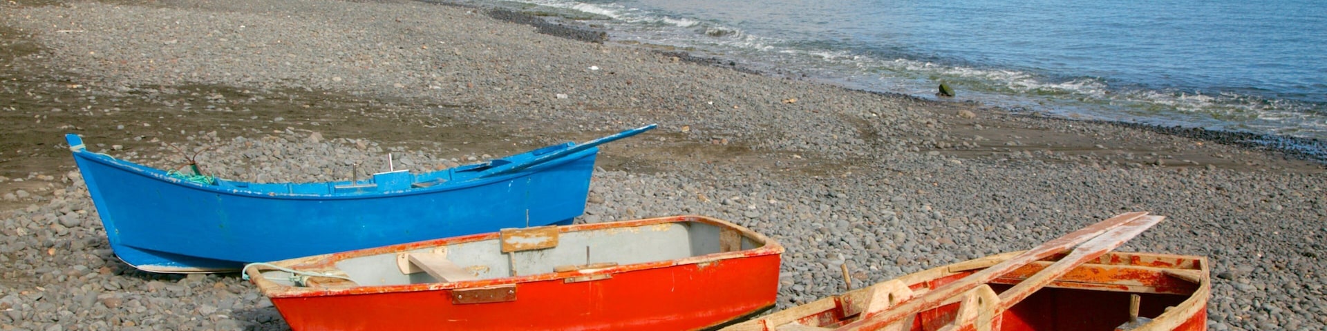 Playa Barca showing boating, rugged coastline and a pebble beach