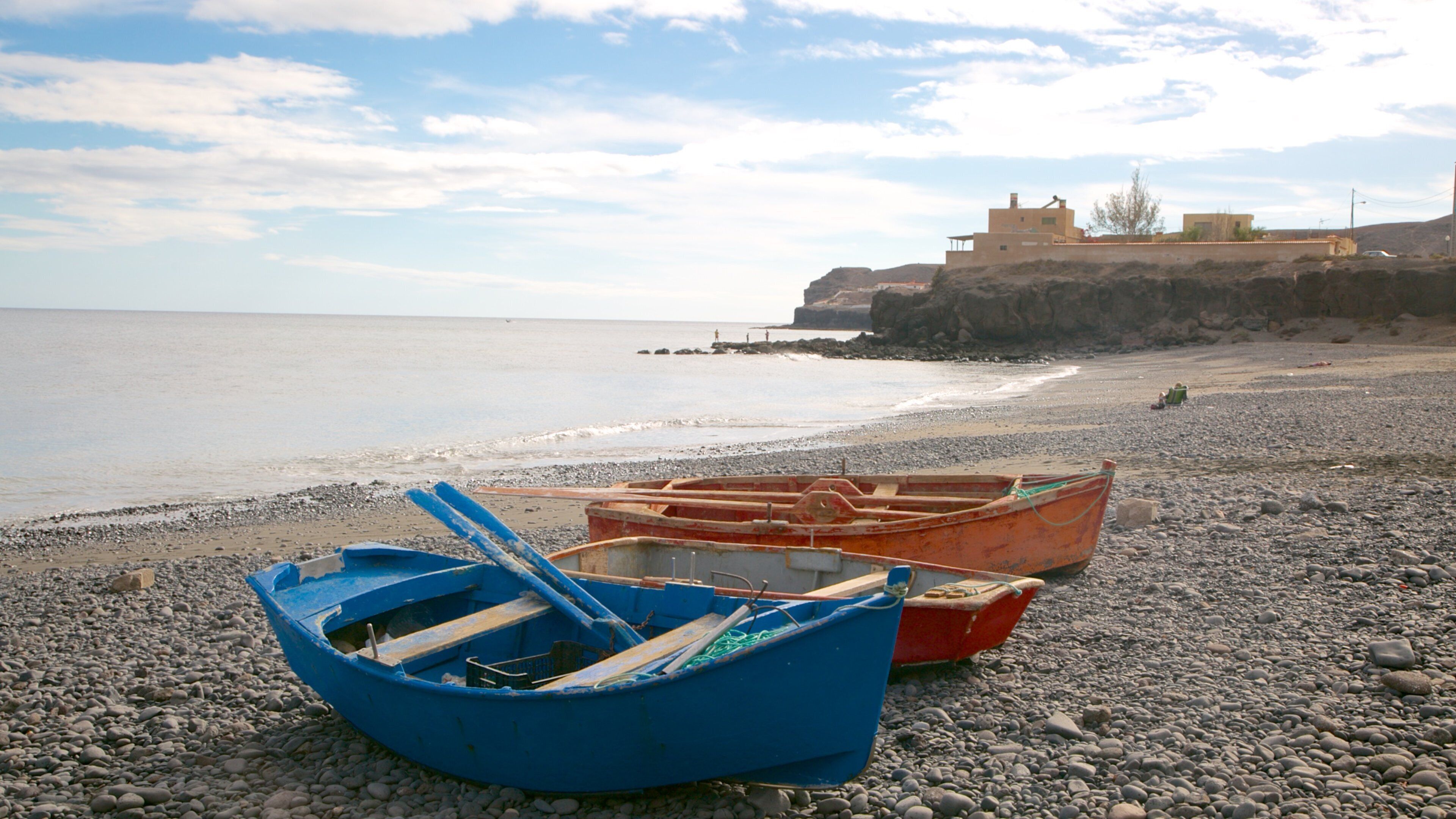 Playa Barca showing a pebble beach, boating and rugged coastline