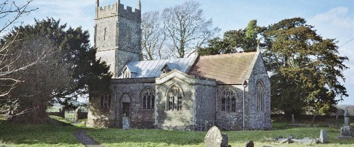 A church with a tall tower and a stone building.