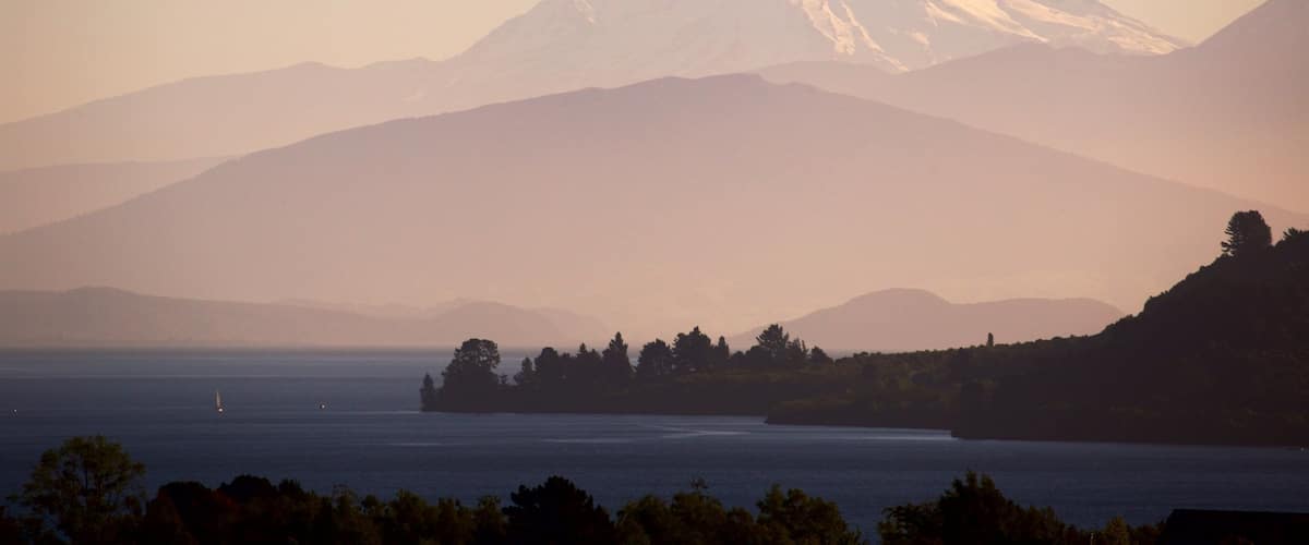 Lake Taupo which includes a sunset, a lake or waterhole and mountains