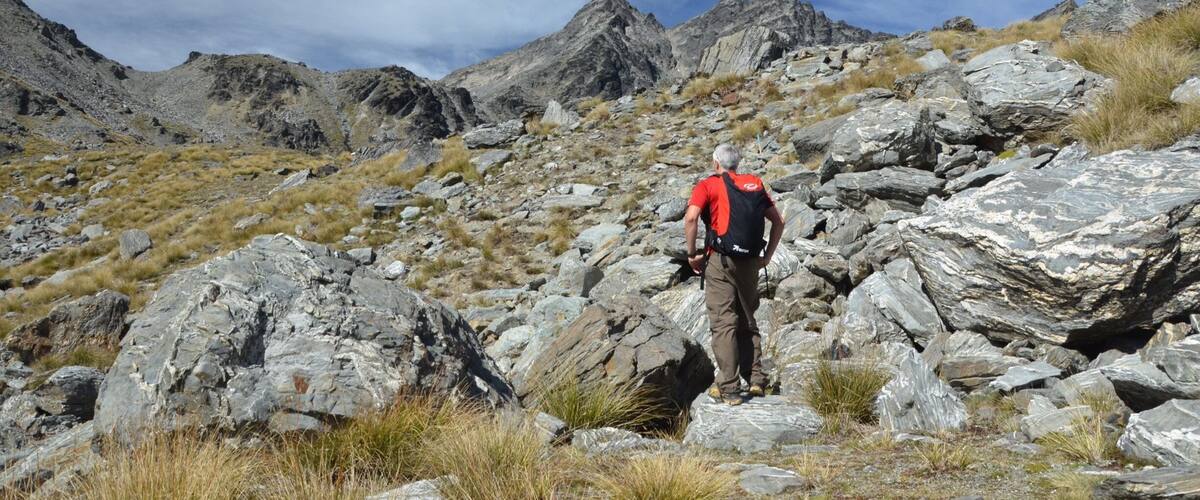 A hiker on rocky terrain with mountains in the background.