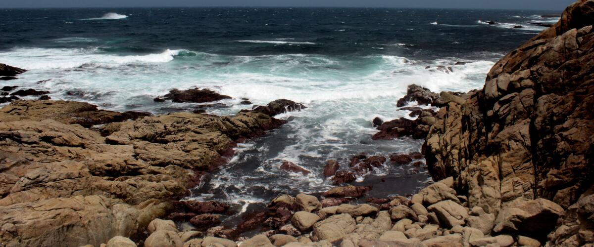 A rocky coastline with turbulent waves crashing against the rocks.