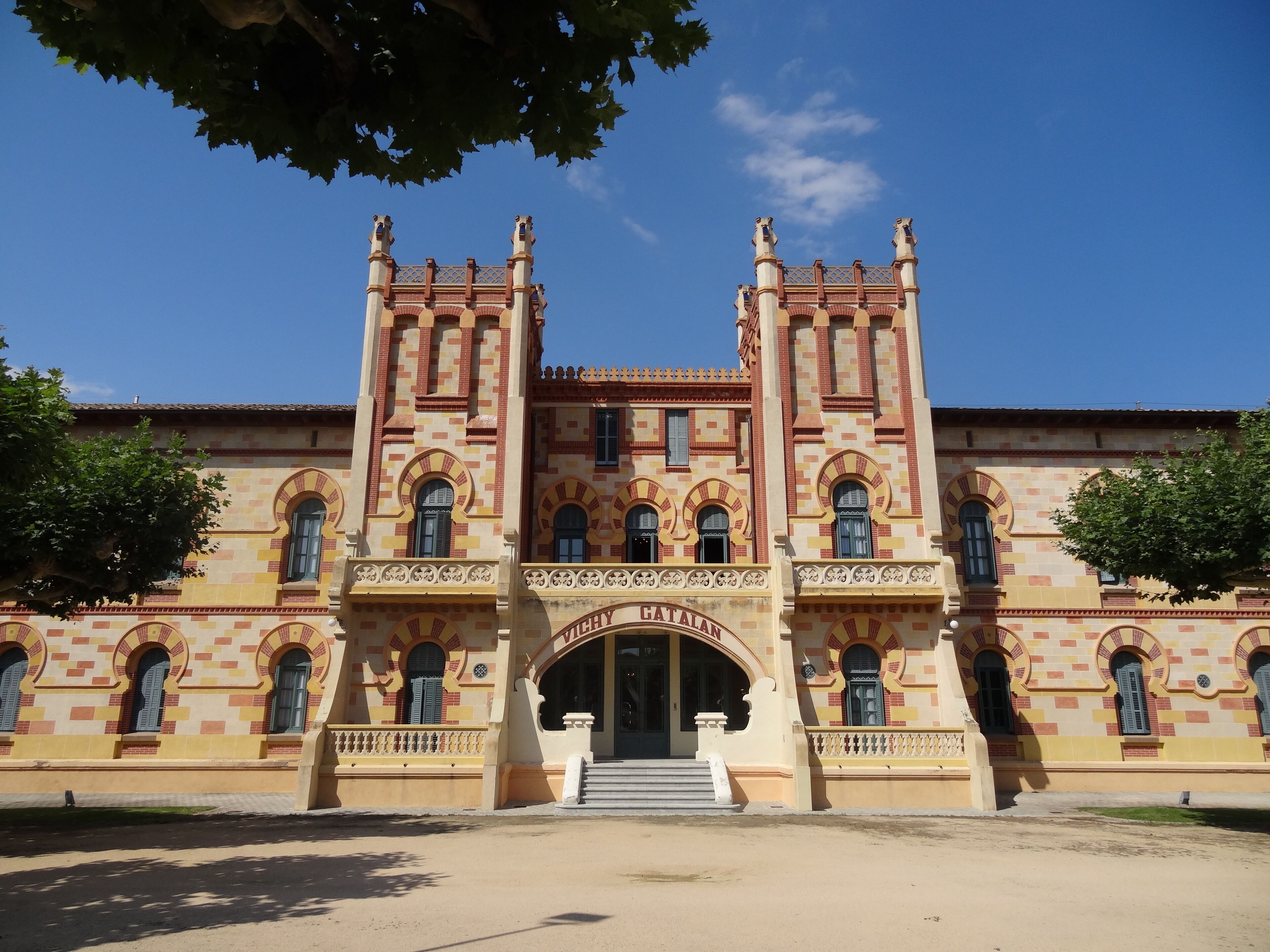 A historic building with a symmetrical facade, arched windows, and a central entrance with steps.