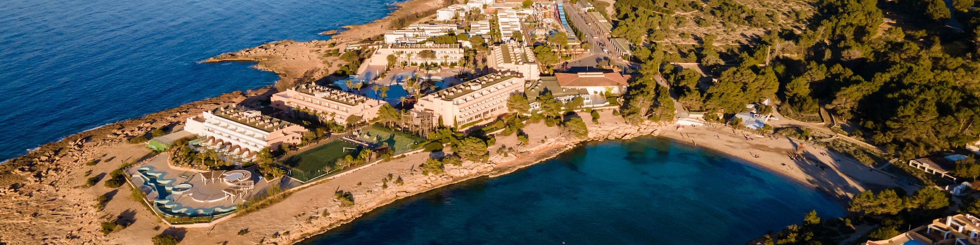 An aerial view of a coastal town with a marina, sandy beaches, and a mix of residential and commercial buildings.
