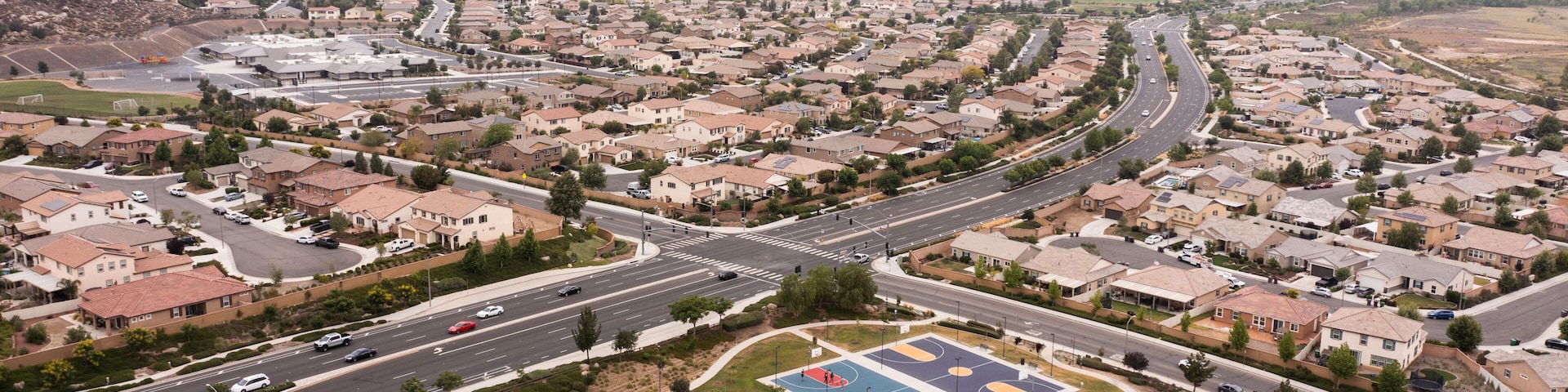 Uma área suburbana com uma quadra de tênis grande, casas residenciais e uma rede de ruas.