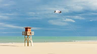 Uma praia com uma torre salva-vidas e um kite a voar no céu.
