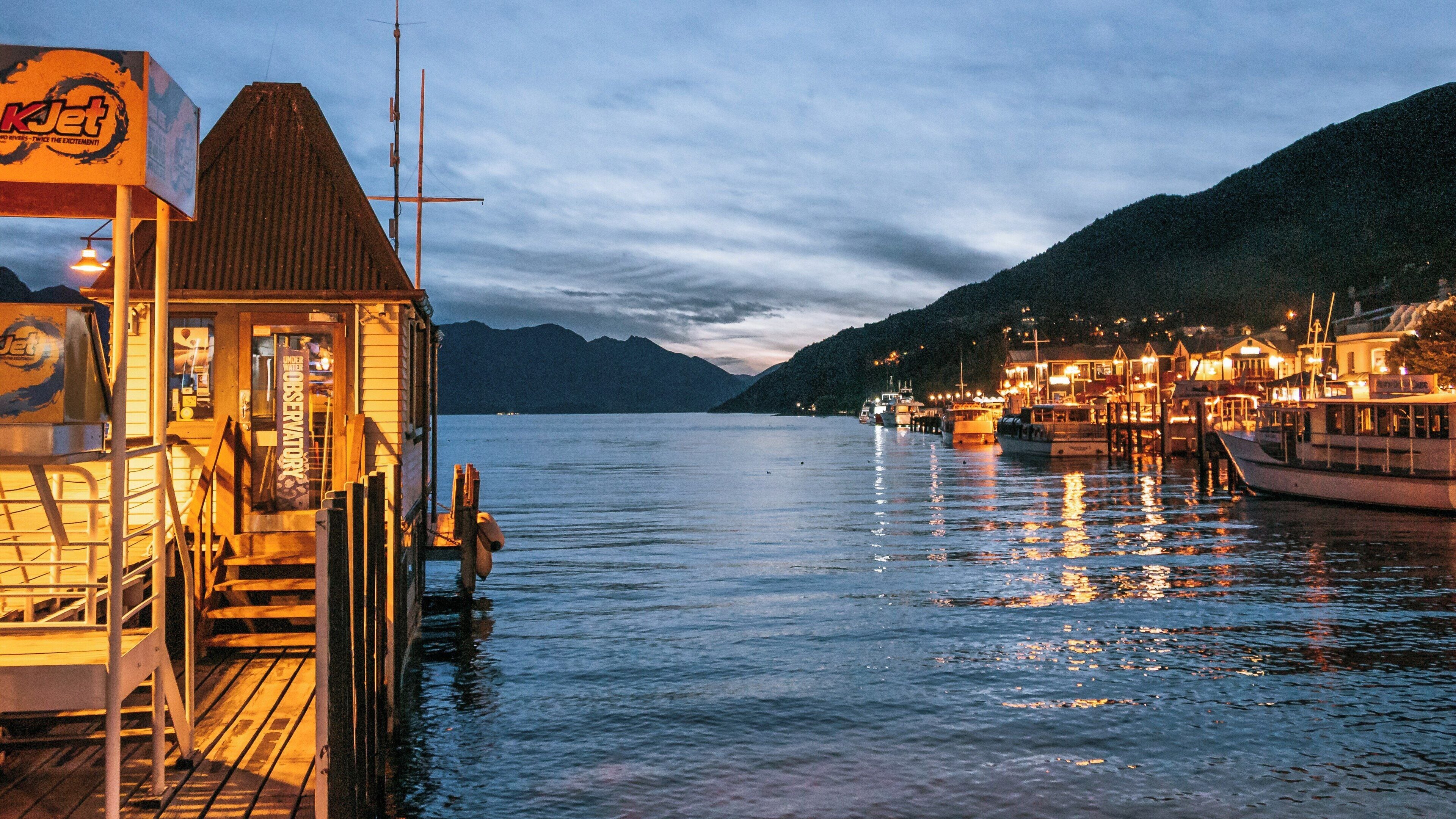 Sunset reflections over Lake Wakatipu with serene waters and illuminated shoreline in Kingston Otago New Zealand