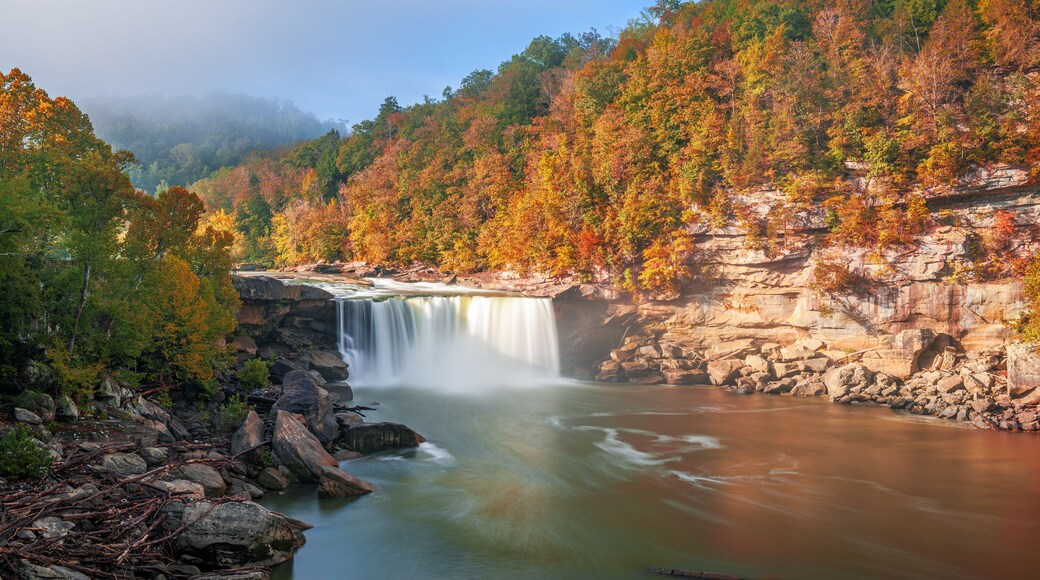 A waterfall cascading over a rocky cliff surrounded by autumn-colored trees.