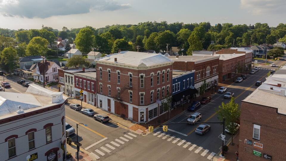 A town square with historic buildings, a crosswalk, and a parking lot.