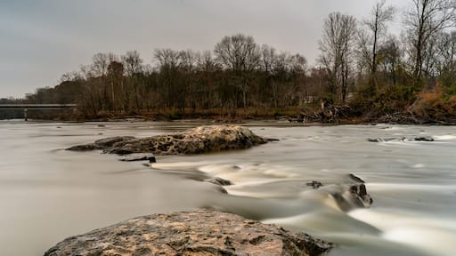 Rocks on a smooth Haw River with a highway bridge in the background