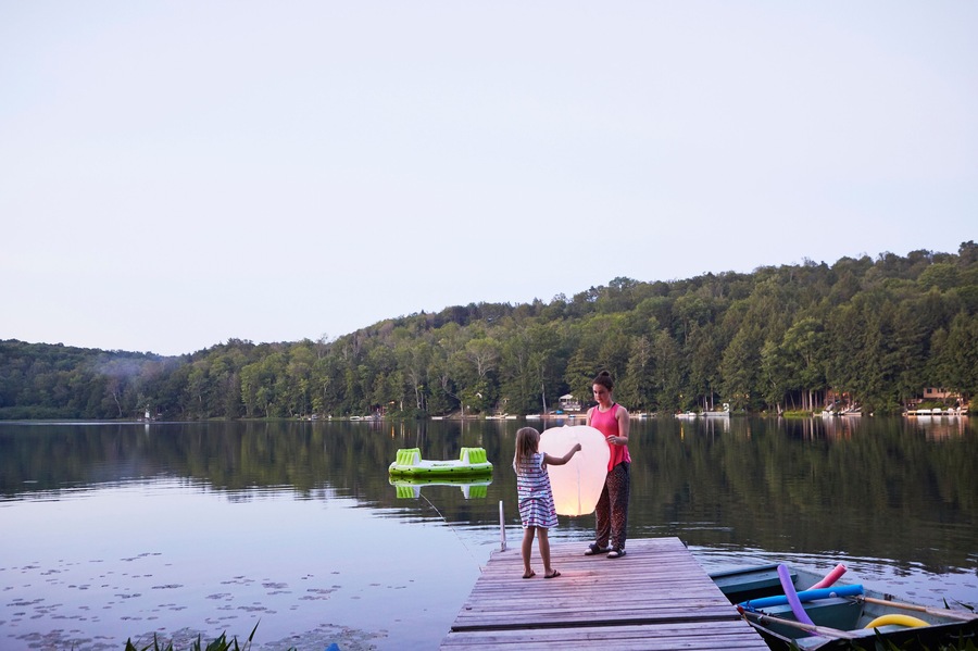 Two girls standing on jetty, releasing sky lantern