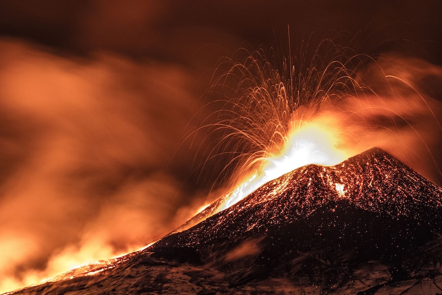 Un volcán en erupción, con lava incandescente y destellos brillantes.