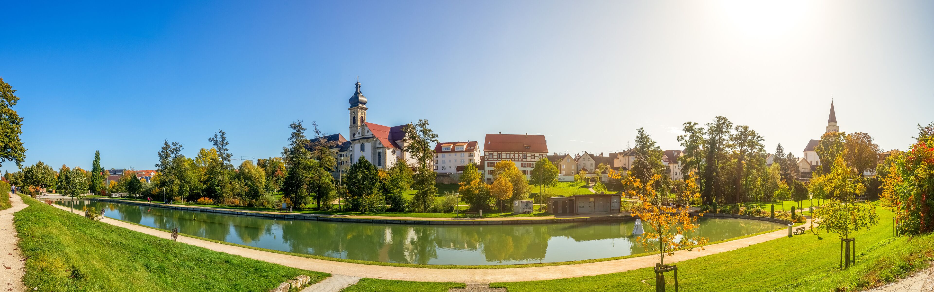 A park with a pond, a church, and residential buildings.