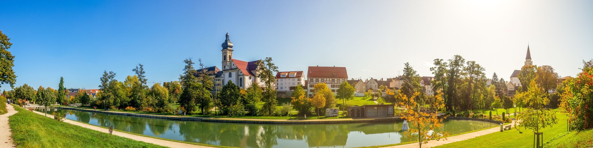 A park with a pond, a church, and residential buildings.