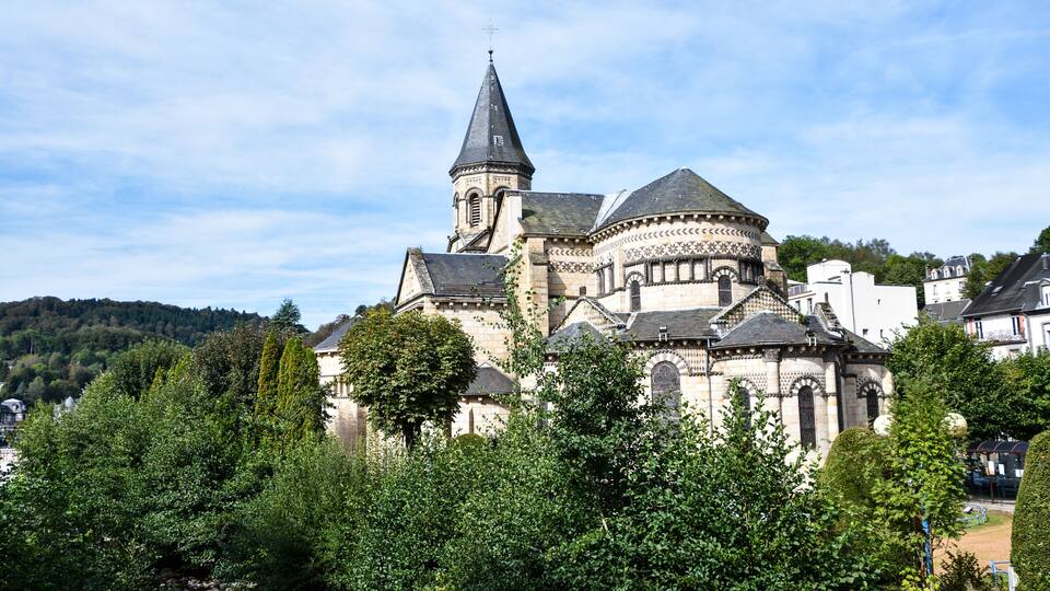 A historic church with a prominent tower and dome, surrounded by lush greenery and residential buildings.