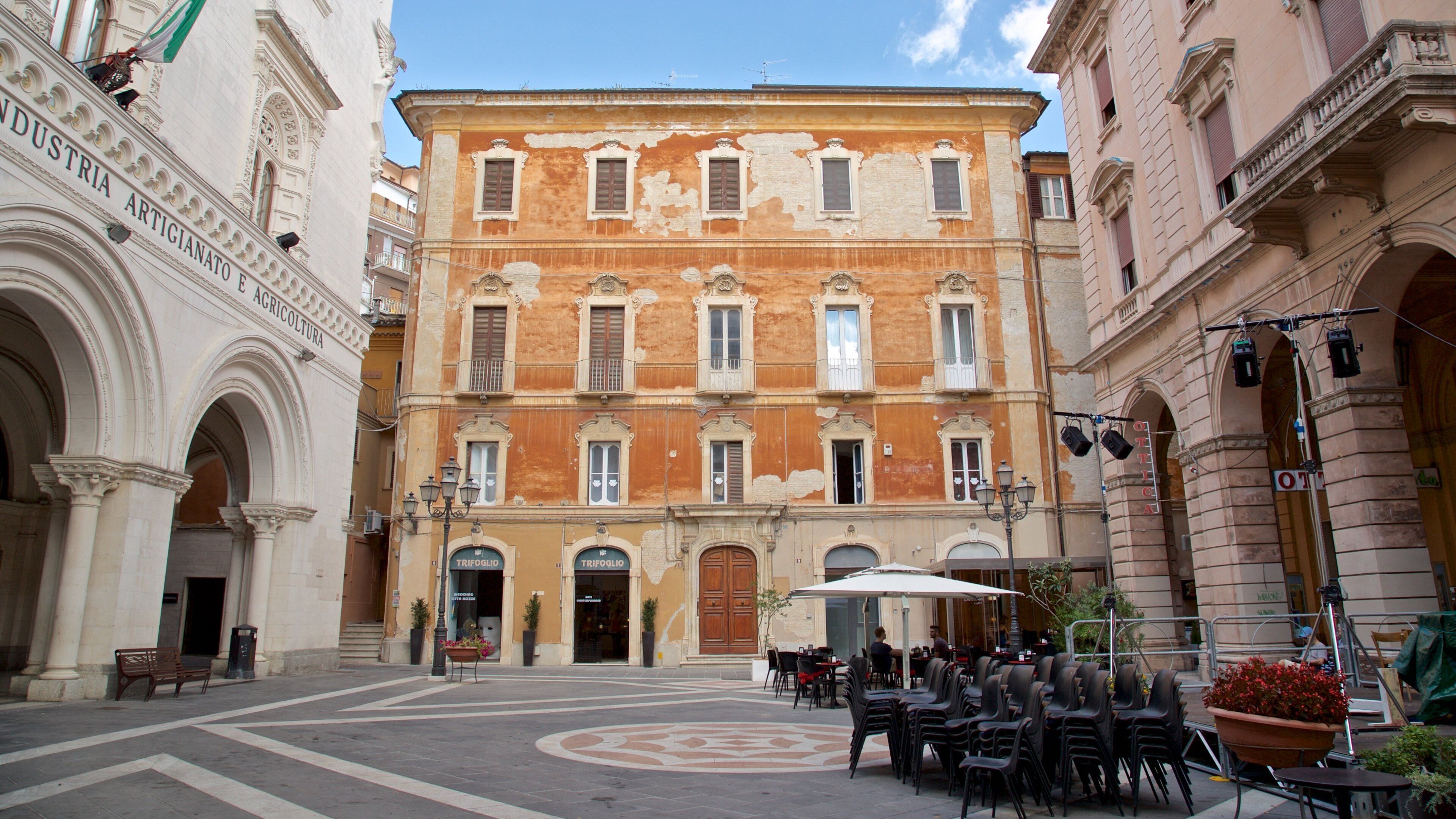 A historic building with ornate architecture, a courtyard with outdoor seating, and a sign reading "TRIFOGLIO".