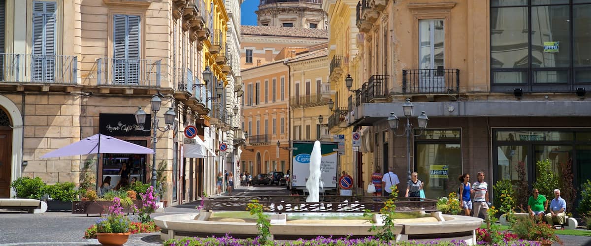 A historic square with a fountain, ornate buildings, and a domed structure in the background.