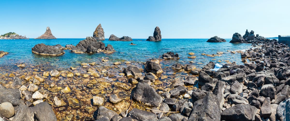 A rocky shoreline with clear blue water and distinctive rock formations.