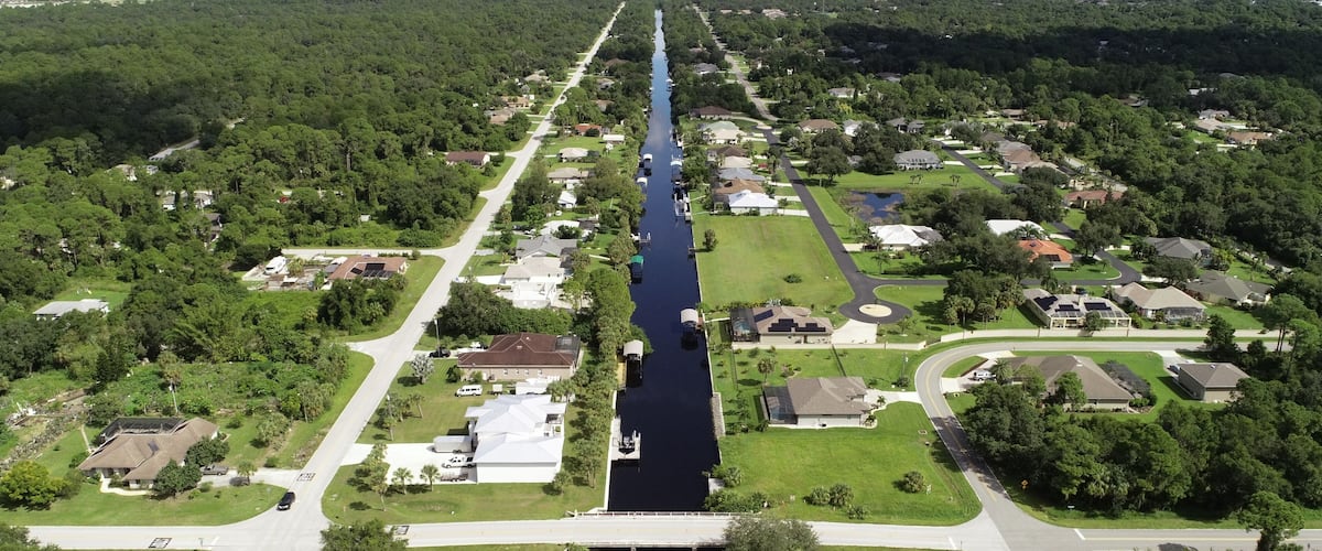 An aerial view of a residential area with a long, narrow waterway running through it.