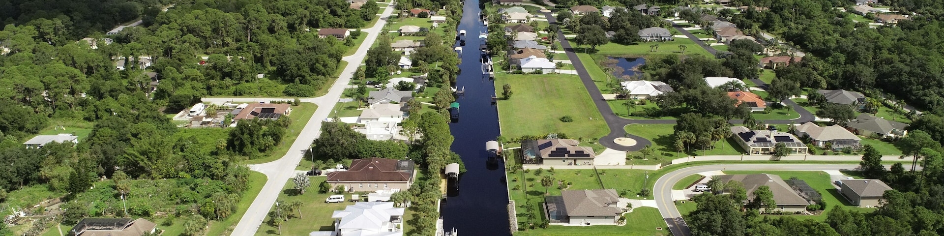 An aerial view of a residential area with a long, narrow waterway running through it.