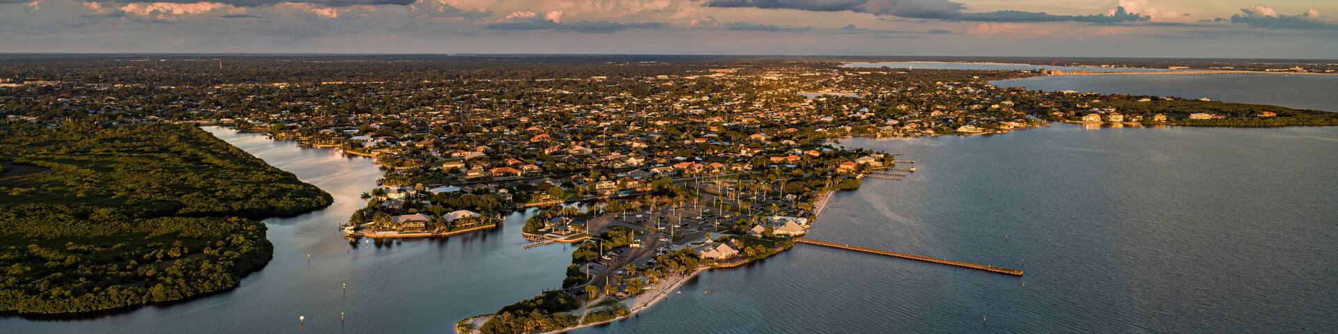 An aerial view of a coastal city with a bay, a peninsula, and a bridge connecting them.