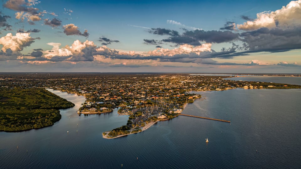 An aerial view of a coastal city with a bay, a peninsula, and a bridge connecting them.