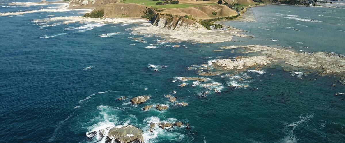 A coastal landscape with rocky outcrops, a bay, and distant mountains.