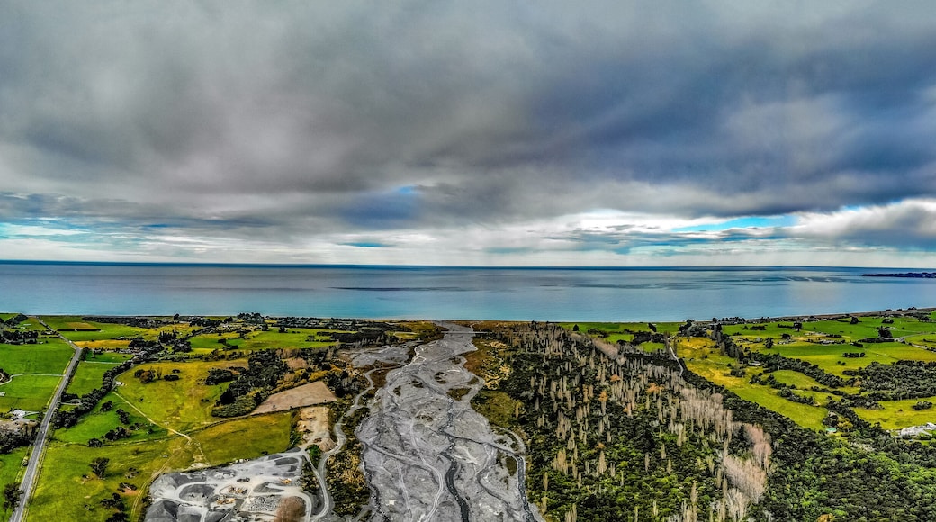 A panoramic photo of Hapuku river delta on the Pacific shore on the South Island of New Zealand under moody sky